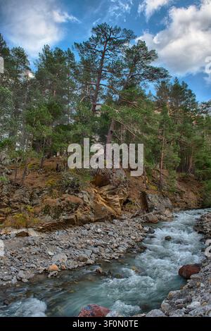 Fast Flowing Rivwer A mountain river flowing along rapids between rocks ends in a waterfall ...