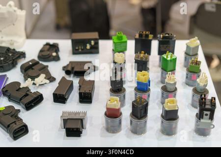 Close-up of various automotive electrical relays, control modules, and electronic components arranged on a white exhibition table. Stock Photo