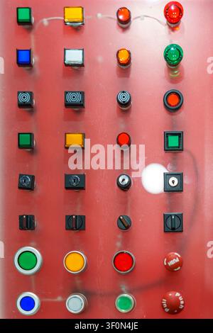 A display board featuring an array of industrial push buttons, indicator lamps, and rotary selector switches in various shapes and colors for machiner Stock Photo