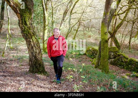 Man in activewear enjoying a peaceful stroll among mossy trees in springtime nature Stock Photo