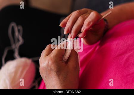 Hands crafting crochet stitch using metal hook and white yarn. Stock Photo