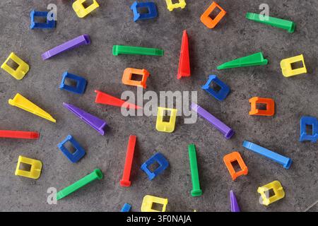 Multicolored plastic clamps and wedges of the tile leveling system on a gray background. Set of bright consumables for construction and repair. Tile l Stock Photo