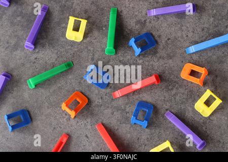 Multicolored plastic clamps and wedges of the tile leveling system on a gray background. Set of bright consumables for construction and repair. Tile l Stock Photo