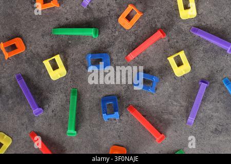 Multicolored plastic clamps and wedges of the tile leveling system on a gray background. Set of bright consumables for construction and repair. Tile l Stock Photo
