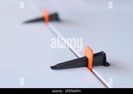Using a plastic wedge and a clamp of a tile leveling system during repair. Professional laying of ceramic tiles on the floor. The process of leveling Stock Photo
