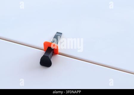 Using a plastic wedge and clamp of a tile leveling system during renovation. Professional laying of ceramic tiles on the floor. The process of levelin Stock Photo