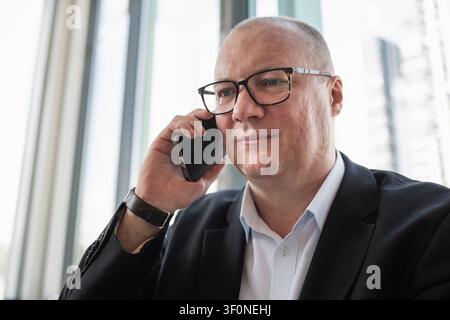 Portrait of confident caucasian businessman talking on smartphone in modern office. Business communication, negotiation and professional networking co Stock Photo