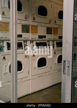 Stacked coin-operated dryers with Japanese instruction labels inside a self-service laundromat in Shibuya, Tokyo, Japan Stock Photo