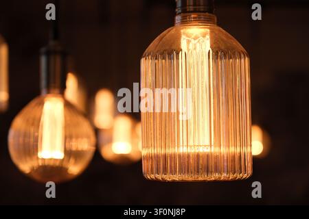 close-up glowing vintage Edison light bulbs hanging indoors, emitting a warm, bright light with a soft bokeh background. Stock Photo