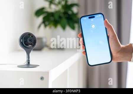 Prague, Czech Republic - June 30, 2026: Smartphone displays the Nest app with a Nest security camera in a modern home interior. Smart home control Stock Photo