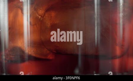 Iced amber liquid with melting cubes in a clear ribbed glass creating texture and refreshment Stock Photo