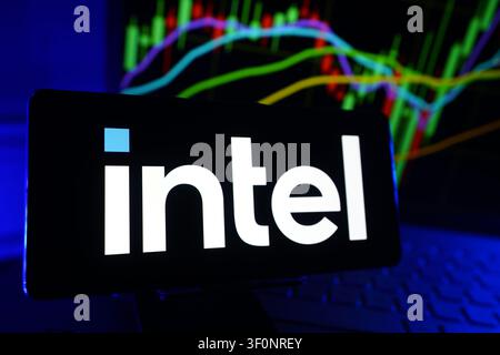 Intel Corporation Logo Displayed On A Smartphone Screen In Front Of A Computer Showing Stock Market Financial Performance Charts Stock Photo