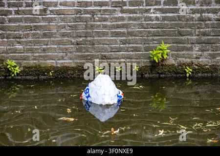 Delft, Netherlands, Europe - July 4 2026: plastic single use shopping bag floating in a Delft canal Stock Photo