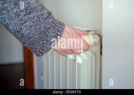 Person regulating room temperature on a heating radiator for comfort and energy saving Stock Photo