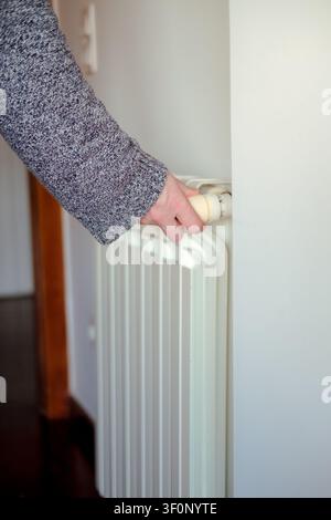 Hand adjusting a radiator thermostat, controlling house temperature and energy usage Stock Photo