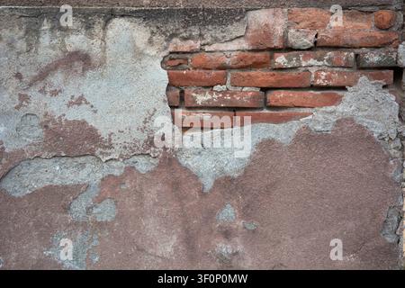 Old wall texture with cracked peeling plaster and exposed red bricks Stock Photo