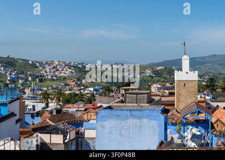 A wider view shows the brick and white-plastered minaret of Sidi Bouhansa Mosque amid the dense blue-painted rooftops and terraced buildings of the me Stock Photo