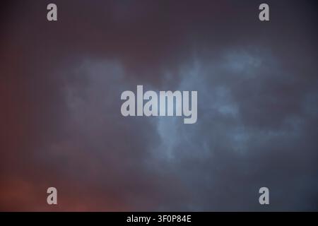 Dramatic Storm Clouds With Blue Opening and Glowing Sunset Light Stock Photo