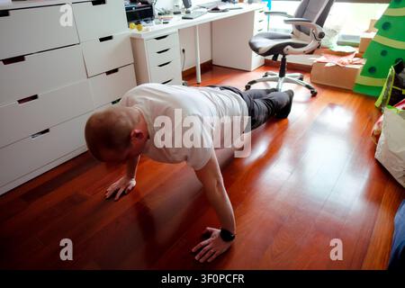 Man exercising at home doing pushups, focusing on fitness and strength training Stock Photo