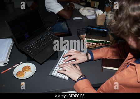 Adult Man Typing Code at Desk in Collaborative Office Stock Photo