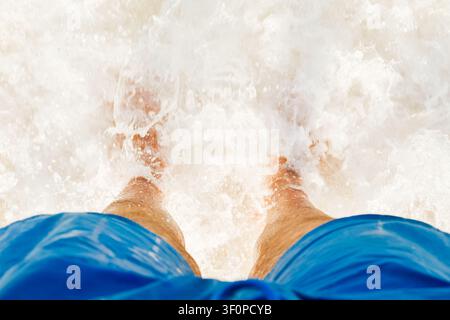 Close-up POV male tourist walking on the unique salt formations and turquoise mineral-rich waters of the Dead Sea beach. A concept for wellness, healt Stock Photo