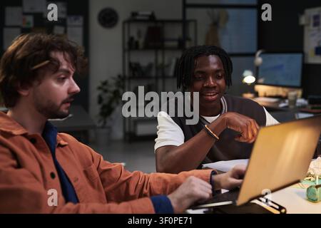 Diverse Adult Men Collaborating on Laptop in Creative Office Stock Photo