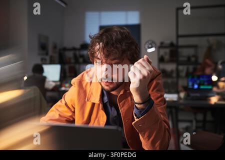 Adult Man Working Late on Laptop in Office under Deadline Pressure Stock Photo