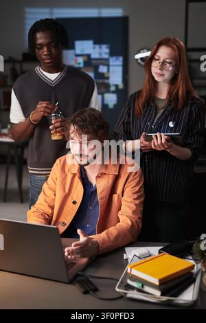 Diverse Adult Coworkers Collaborating on Laptop in Creative Office Stock Photo