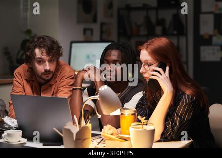 Diverse Adult Colleagues Working Late on Project Call in Office Stock Photo