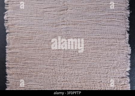 Full Beige Crinkled Muslin Fabric Piece on Black Surface Stock Photo