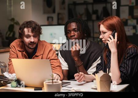 Diverse Coworkers Collaborating on Laptop during Client Call Stock Photo