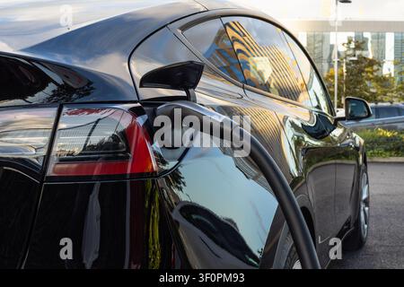 Electric vehicle charging at a public station Stock Photo