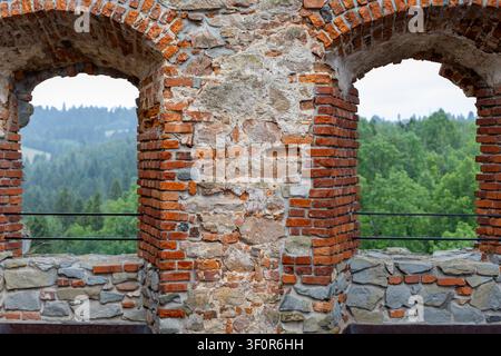 Weathered brick arches overlooking forest valley. Weathered brick and stone arches frame a green forested valley, showing rough masonry textures and Stock Photo