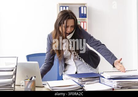 Young female employee unhappy with excessive work Stock Photo