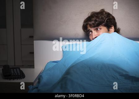 Young man scared in his bed having nightmares Stock Photo