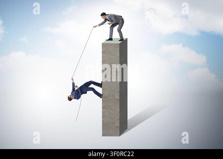 Businessman helping colleague with rope Stock Photo