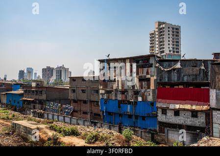 A Mumbai cityscape highlights strong social contrast, showing multilevel slum dwellings made of rusty and colorful corrugated sheets in the foreground Stock Photo