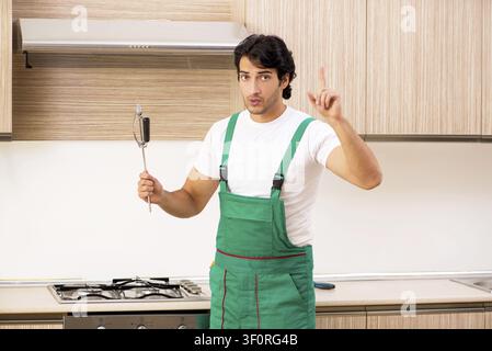 Young contractor repairing oven in kitchen Stock Photo
