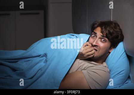 Young man scared in his bed having nightmares Stock Photo