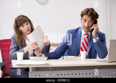 Two colleagues having lunch break at workplace Stock Photo