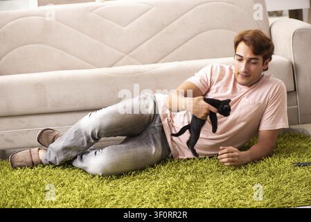 Young man playing with kitten at home Stock Photo