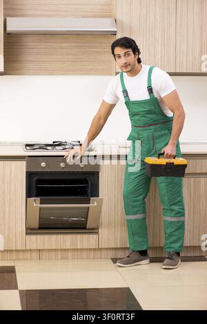 Young contractor repairing oven in kitchen Stock Photo