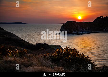 Glorious sunset over the calm sea and rugged rocks at Lulworth Cove on the Jurassic Coast in Dorset England - serene coastal landscape Stock Photo
