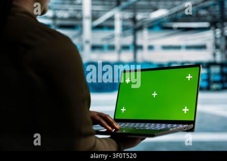 Data center programmer works with a chroma key laptop, using an editable screen to expand workload capacity. Stock Photo
