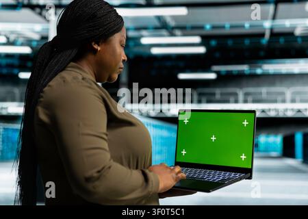 Data center engineer works with a chroma key laptop, using an editable screen to expand workload capacity. Stock Photo