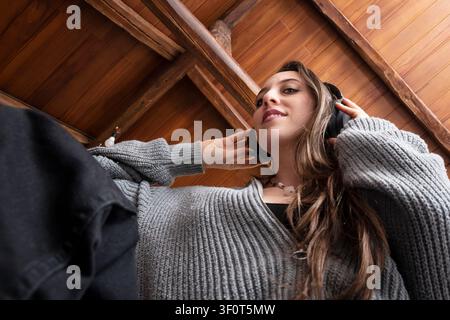 Low Angle View of Young Woman Enjoying Music with Wireless Headphones Indoors Stock Photo
