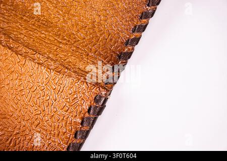 Close-up textured leather detail with embossed pattern, reinforced edges, neat stitching, light gray background, rich brown colors, professional style Stock Photo