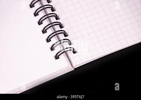 Spiral notebook with grid pages, white paper, black binding, clean composition, simple studio environment, even soft lighting, professional clarity, m Stock Photo