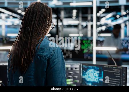 Woman working with AI tech in server room storing data used for machine learning. Stock Photo
