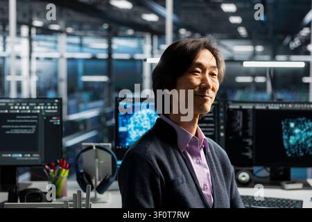 Smiling senior programmer in server room working on databases supporting AI applications. Stock Photo